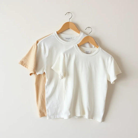 Neatly folded cotton t-shirts in different fits on a light neutral background
